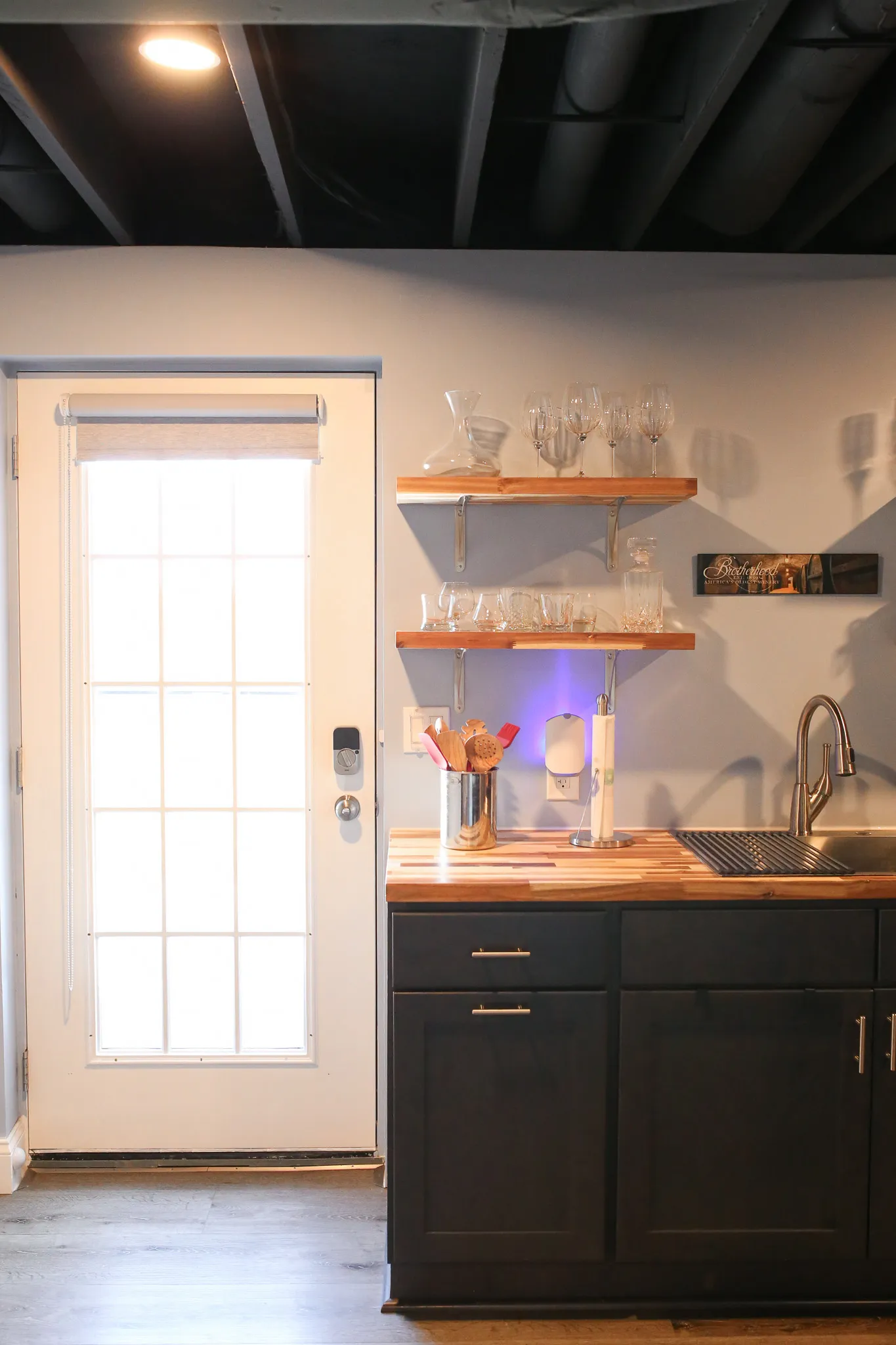 Basement wetbar with black cabinets and butcher block countertop